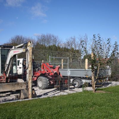 Et højt Multinet hegn på Økopæle beskytter en virksomheds maskiner