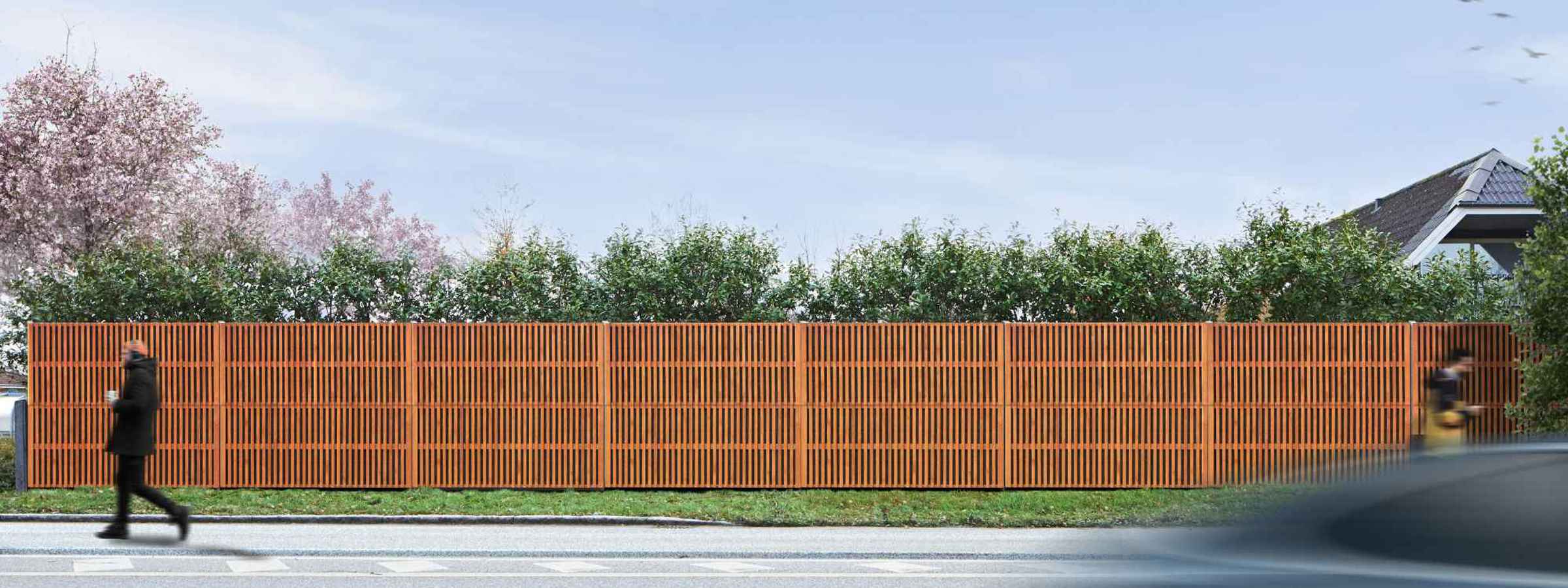 Noistop Essential støjhegn med sort ramme, fuldt dækket af tilvalgte træpaneler. En fodgænger går forbi, og en bil passerer på vejen.