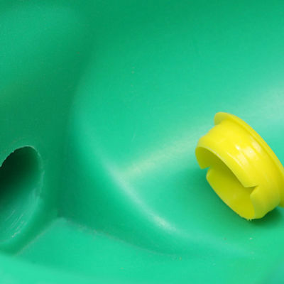 Nærbillede af en grøn drikkekop med en gul plastprop ved en åbning