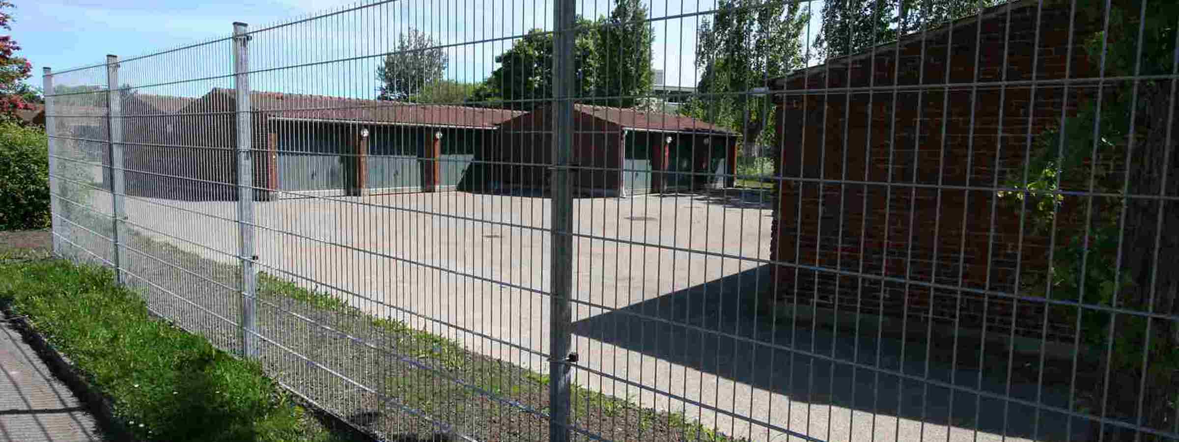 På en politiskole er der opsat et gråt panelhegn for at øge sikkerheden