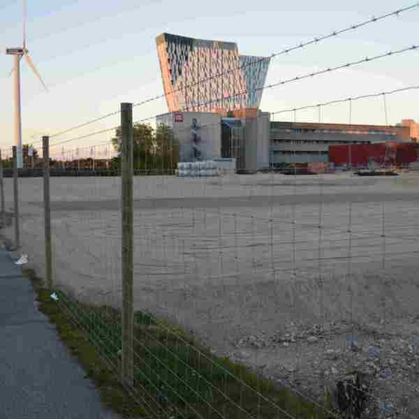 En byggeplads er beskyttet med et nethegn med to pigtråde monteret ovenpå