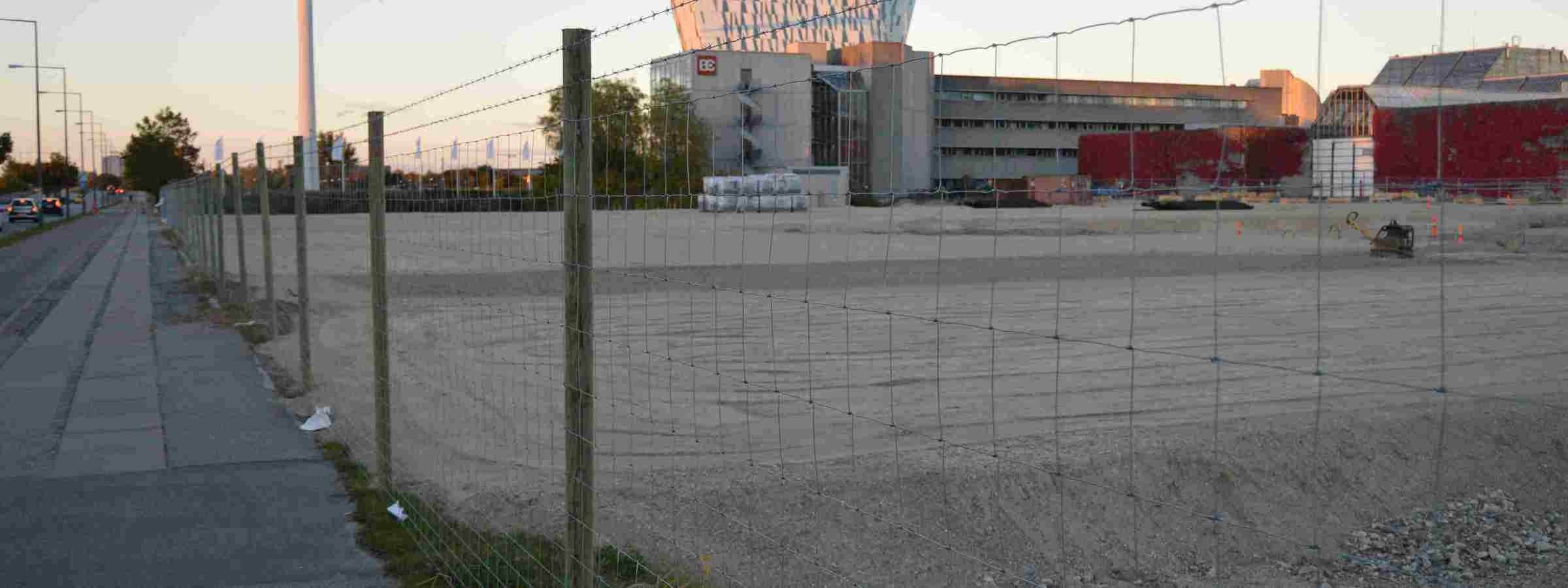 En byggeplads er beskyttet med et nethegn med to pigtråde monteret ovenpå