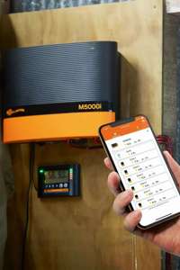 Strømgiver M5000 der hænger på en væg, hvor den tilhørende telefon app bliver vist frem