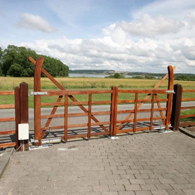 Ud til en vej er der monteret en Country Ranger låge. I baggrunden er en mark og en sø