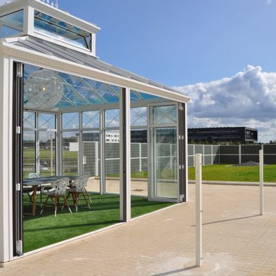 Pavillon med store panoramavinduer på en virksomheds fællesareal afskærmet med Noistop® Steel støjhegn fra Poda Hegn