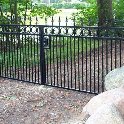 En smedejernslåge i sort med lige top er monteret i en indkørsel