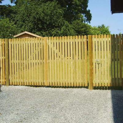 En høj dobbelt port og en ganglåge danner indgangspartiet til en have