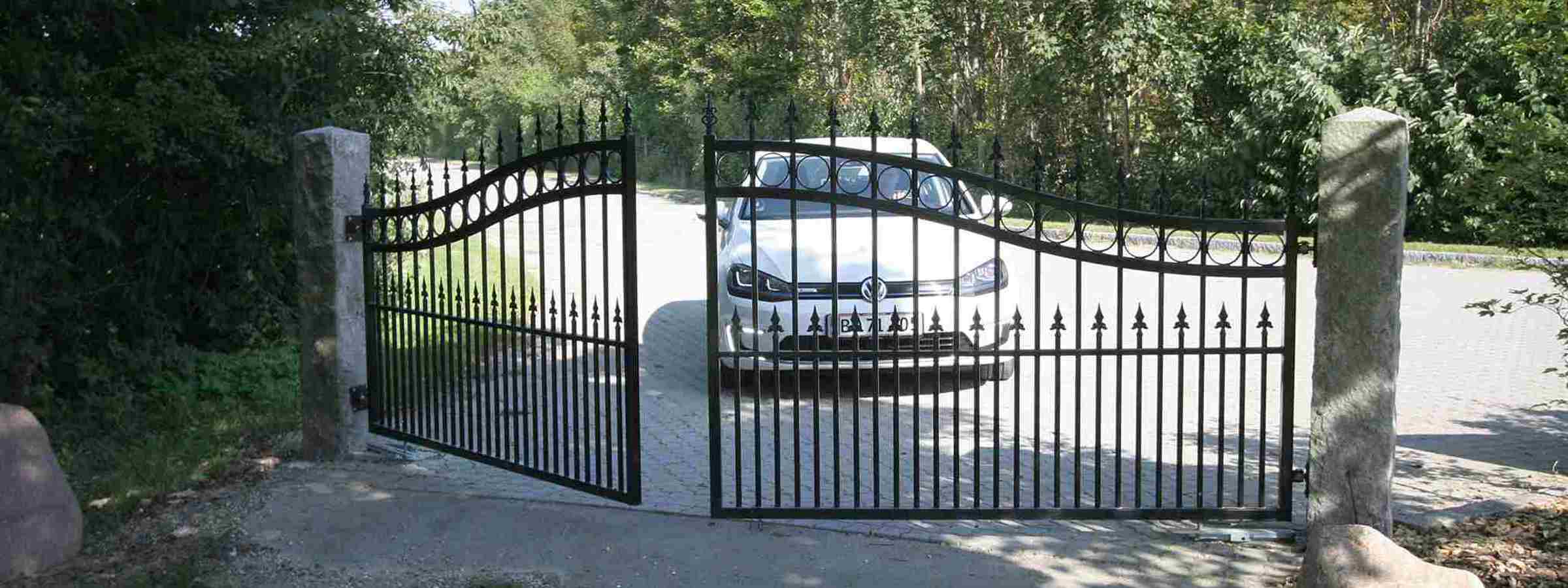 En bil holder bag en smedejernslåge med port automatik som er ved at åbne