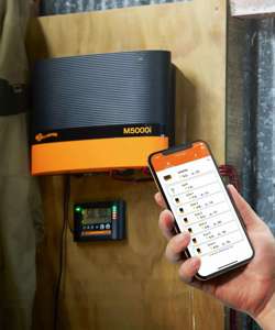 Strømgiver M5000 der hænger på en væg, hvor den tilhørende telefon app bliver vist frem