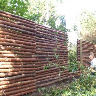 En mand er i gang med at montere et hegnsfag af granraftehegn