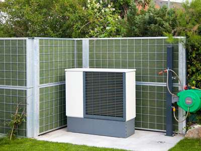 Et Noistop® Steel støjhegn fra Poda Hegn opsat i en have til afskærmning af støj fra en varmepumpe