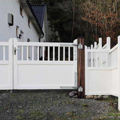 Midt på en hegnslinje er der monteret en Country Garden låge, som er malet hvid ligesom hegnet