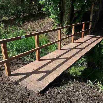 Flot bro i træ med gelænder i den en side, fører dig sikkert over åen