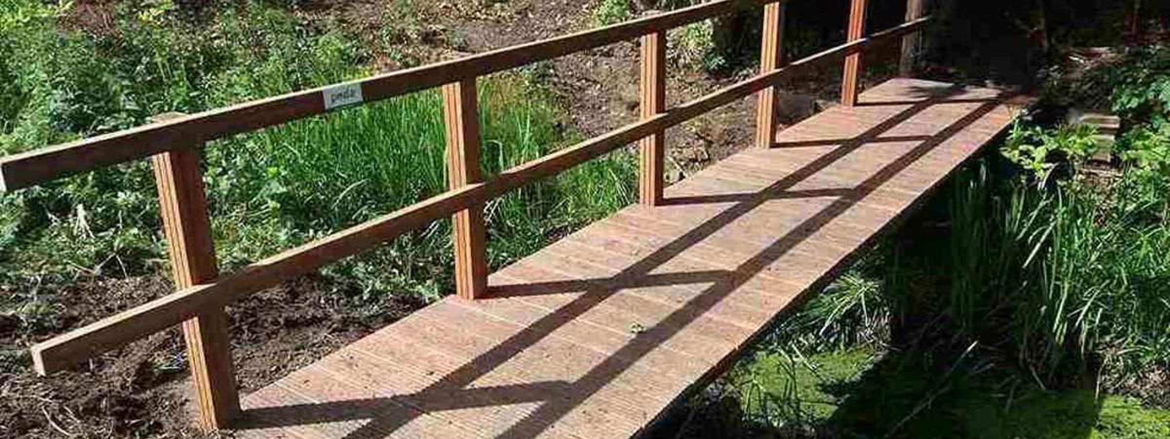 Flot bro i træ med gelænder i den en side, fører dig sikkert over åen