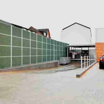 Et Noistop® Steel støjhegn fra Poda Hegn opsat ved vareindleveringen til et supermarked