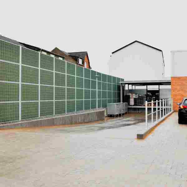 Et Noistop® Steel støjhegn fra Poda Hegn opsat ved vareindleveringen til et supermarked