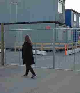 En dame går foran en letvægtslåge, der er monteret ved en byggeplads