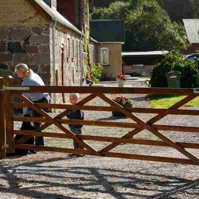 En hund, en kvinde og en dreng står bagved en Country House låge