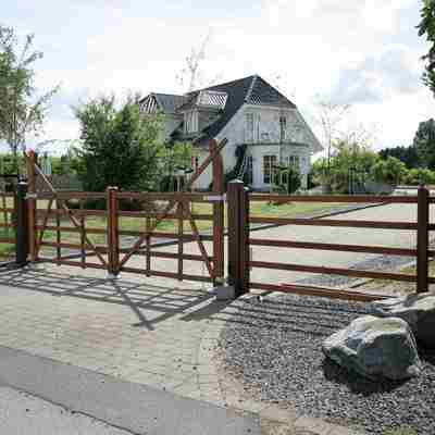 Fra en vej kan man se en indkørsel, som er indhegnet med en Country Ranger låge