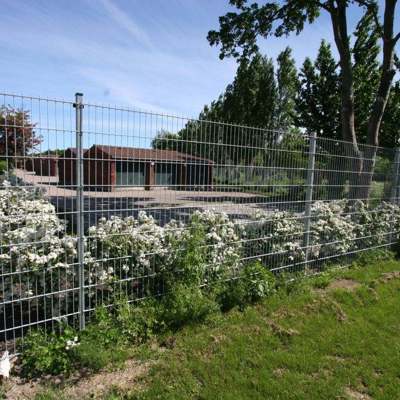 Et panelhegn i grå beskytter en parkeringsplads