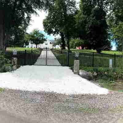 Fra en panorama vinkel kan man se en smedejernslåge i sort, som er monteret ved siden af hegn i samme design