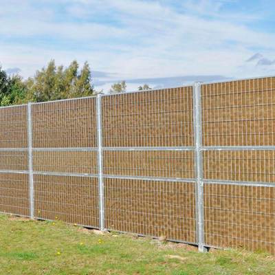 Noistop Essential støjhegn med galvaniseret stålramme og metalpaneler, monteret på en græsplæne i et åbent område.