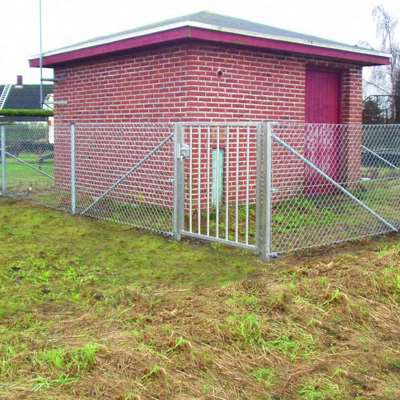 En lille rød bygning er beskyttet af et flethegn