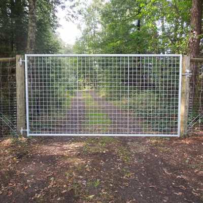 I forgrunden er der en letvægtslåge med gitter. Bagved er der en sti i en skov