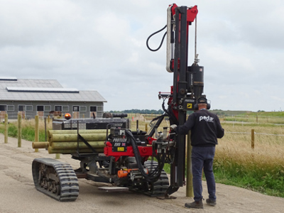 En Poda-montør bruger en pælehammer til opsætning af hegn på en landejendom.