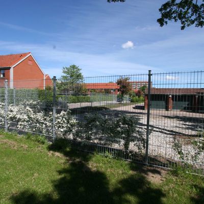 Et panelhegn i grå beskytter en parkeringsplads