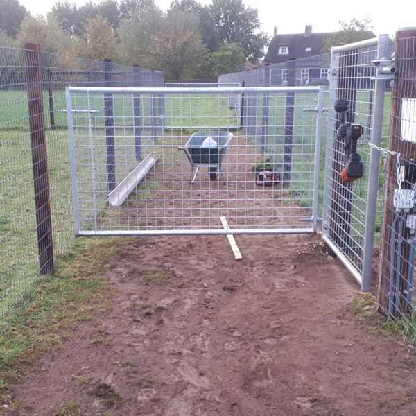 En trillebør står bag en letvægtslåge med gitter