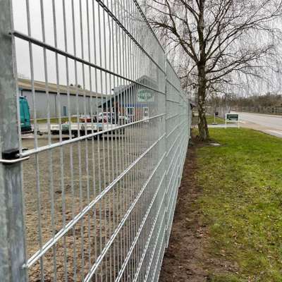 I et industri område er der monteret et gråt panelhegn for at beskytte en virksomhed