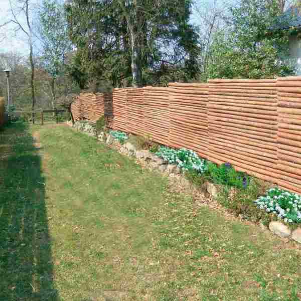 Et hegn lavet af runde granrafter er sat op langs med en sti