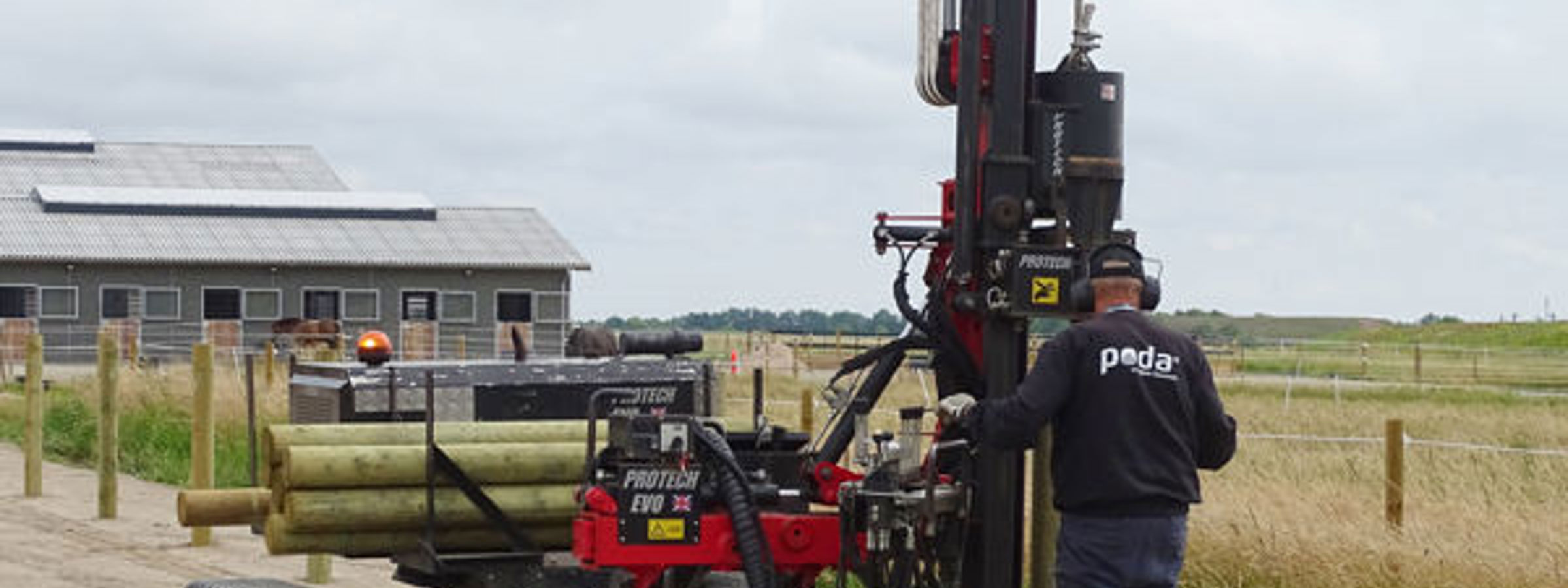 En montør der er i gang med at sætte lægter i jorden til et nyt hestehegn