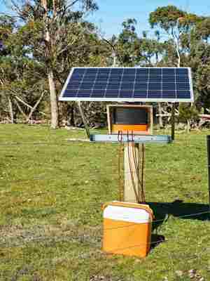 Soldrevet strømgiver står på en mark op af et hegn