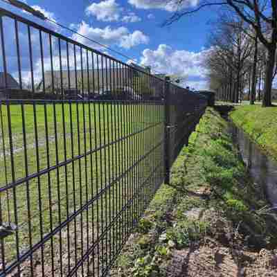 På et panelhegn ud til en å, er der monteret to strømførende tråde for at øge sikkerheden