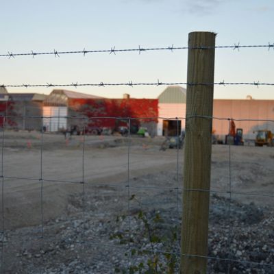 På en hegnspæl er der monteret et byggepladshegn samt to rækker pigtråd
