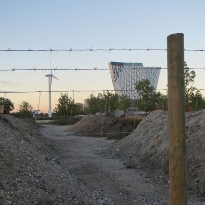 Et byggepladshegn bestående af trykimprægnerede pæle, et nethegn og to rækker pigtråd