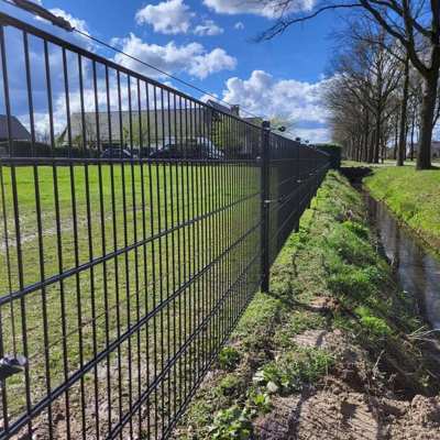 På et panelhegn ud til en å, er der monteret to strømførende tråde for at øge sikkerheden